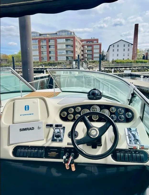 Slide: The Image of 2000 Cruisers Yachts 3772 Express helm with modern controls, docked near waterfront buildings. - 6