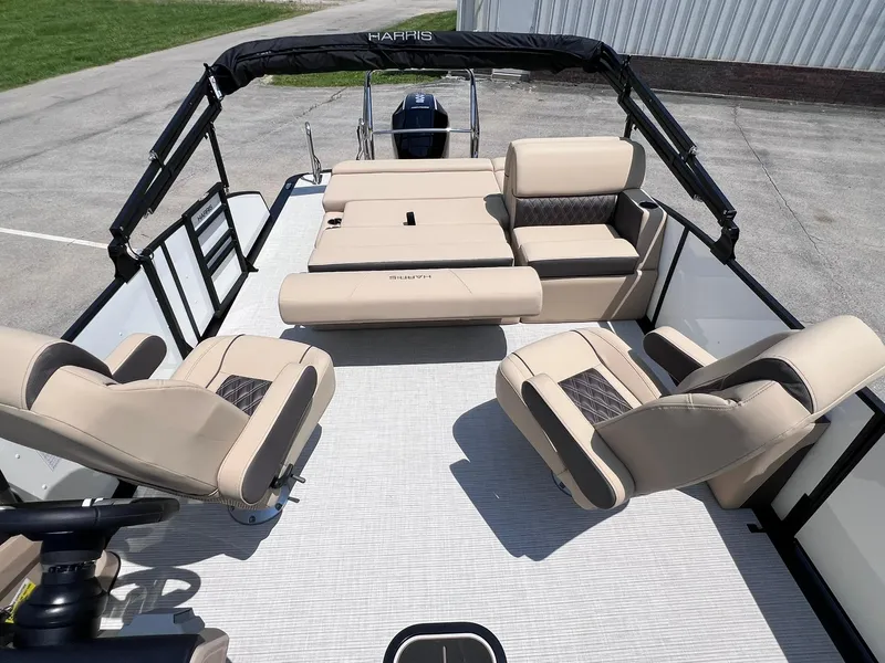 Slide: The Image of 2025 Harris Sunliner 230 pontoon boat with beige seating and black canopy. - 11