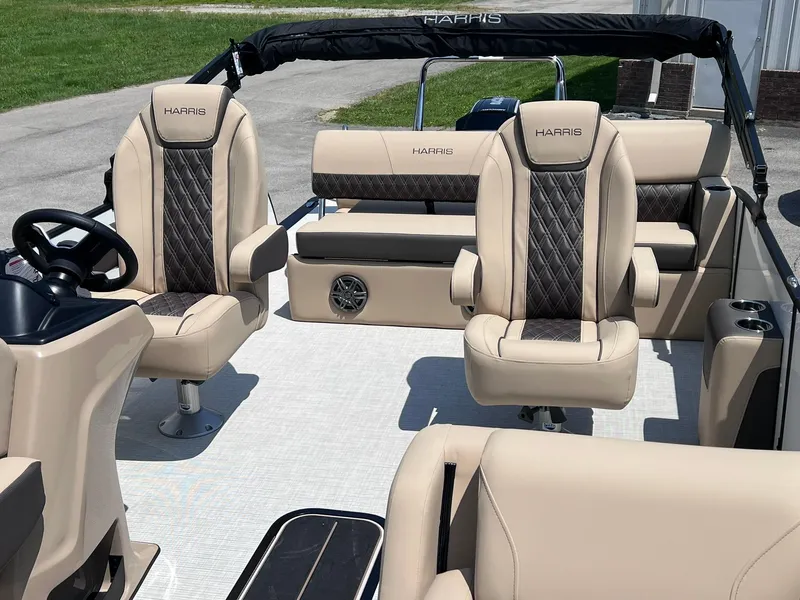 Slide: The Image of 2025 Harris Sunliner 230 boat interior with beige and black seating, steering wheel, and spacious layout. - 9
