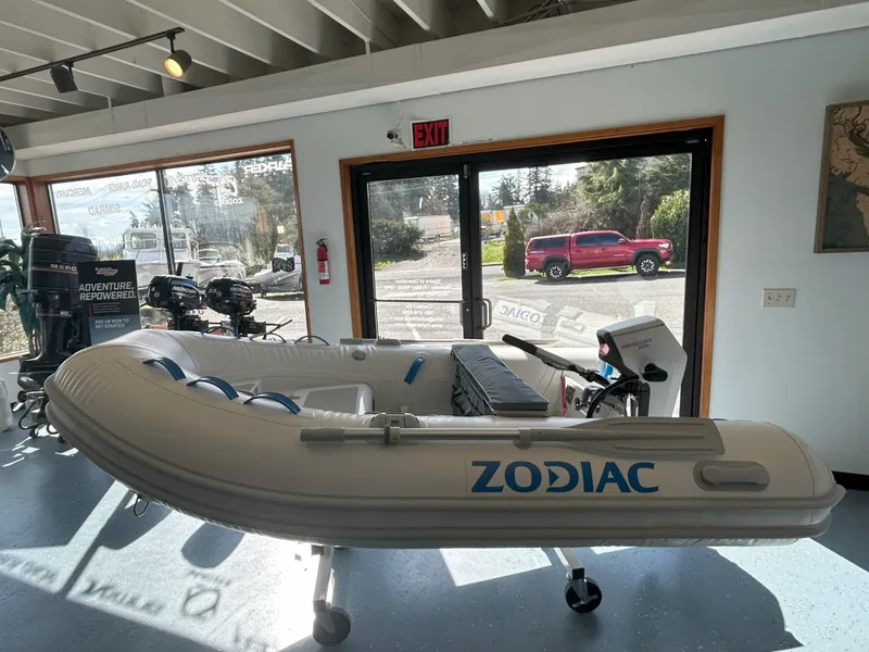 Slide: The Image of 2024 Zodiac Nomad 3.1 RIB Alu inflatable boat displayed indoors, with sunlight streaming through windows. - 13
