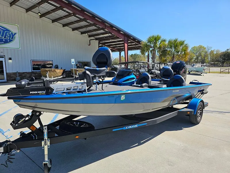Slide: The Image of 2022 Vexus AVX1880 boat with trailer, parked outdoors near a building. - 2