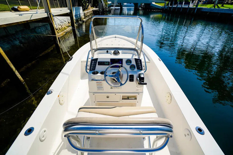 Slide: The Image of 2016 Robalo 206 Cayman boat interior with steering wheel, console, and seating, docked by a canal. - 17