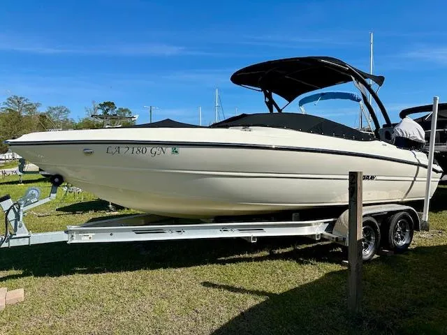 Slide: The Image of 2021 Stingray 225 SE boat on trailer, parked on grass under clear blue sky. - 0