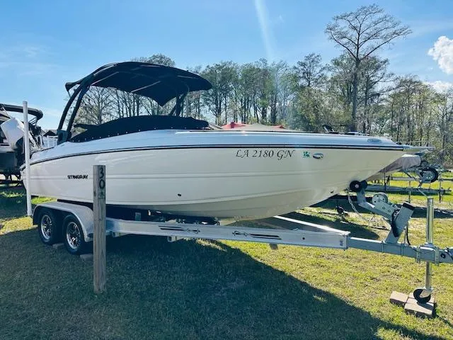 Slide: The Image of 2021 Stingray 225 SE boat on trailer, parked outdoors with trees in the background. - 1