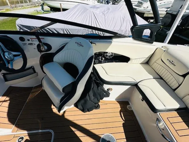 Slide: The Image of 2021 Stingray 225 SE boat interior with white seating and wood flooring. - 12