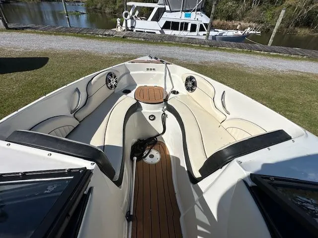 Slide: The Image of 2021 Stingray 225 SE boat interior with seating and speakers, docked near a waterway. - 18