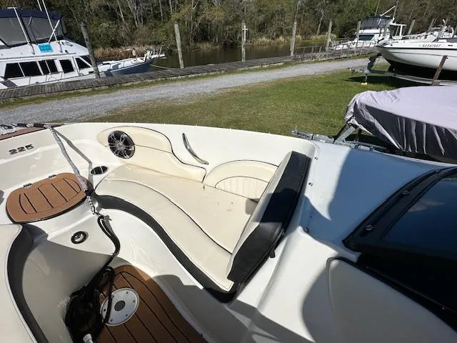 Slide: The Image of 2021 Stingray 225 SE boat interior with seating, docked near grassy area and other boats. - 19