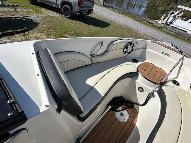 Slide: The Image of 2021 Stingray 225 SE boat interior with seating and wood accents near a lake. - 20