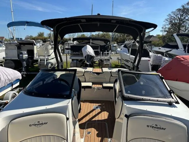 Slide: The Image of 2021 Stingray 225 SE boat with open cockpit, docked among other boats. - 24