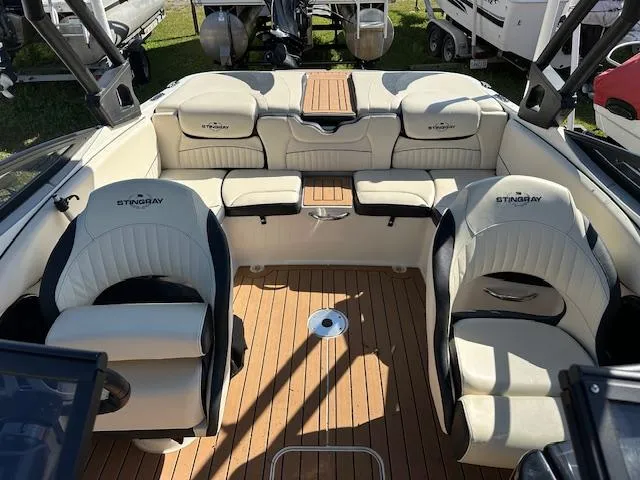 Slide: The Image of 2021 Stingray 225 SE boat interior with beige seating and wood flooring. - 25