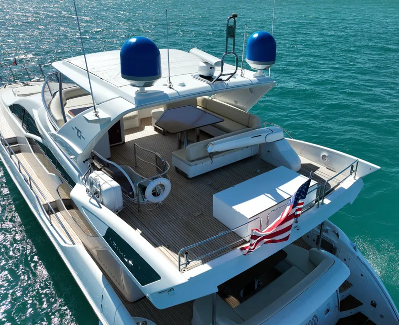 Slide: The Image of Luxury 2014 Azimut 70 yacht on clear blue water, featuring spacious deck and American flag. - 14