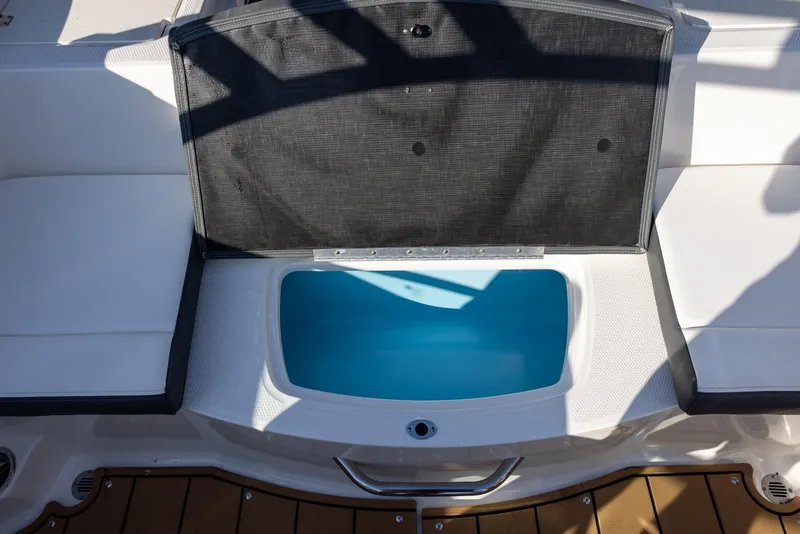 Slide: The Image of 2023 Chaparral 21 SSi OB boat storage compartment with open lid, revealing blue interior. - 9