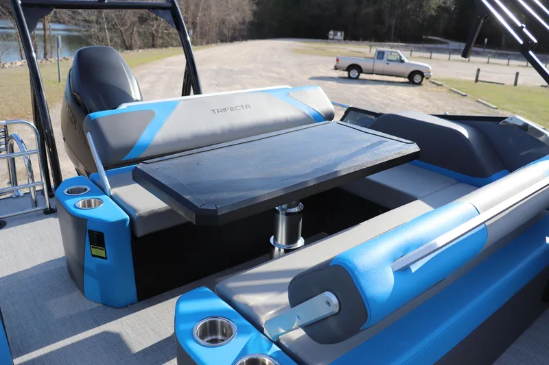 Slide: The Image of 2025 Trifecta 23 ULE boat interior with seating and table, parked near a lake. - 10