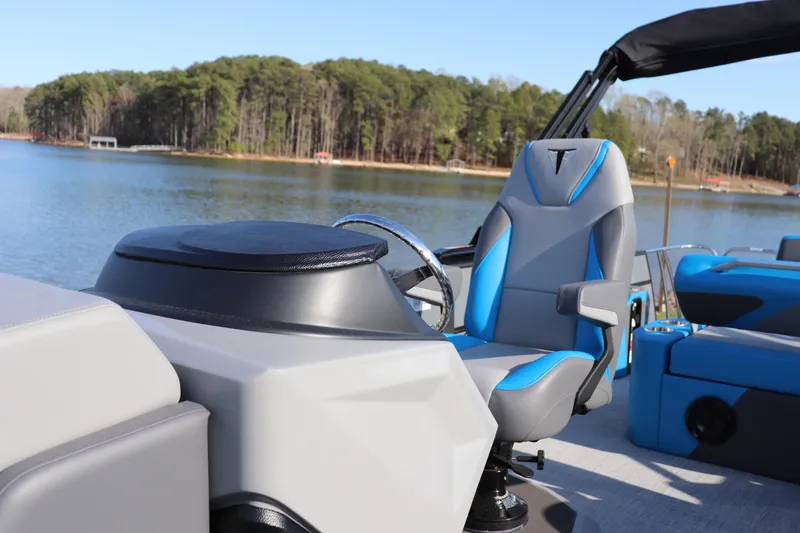 Slide: The Image of 2025 Trifecta 23 ULE boat interior with blue and gray captain's chair on a lake. - 6