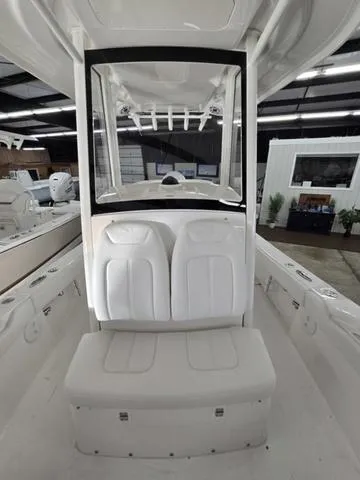 Slide: The Image of 2025 Regulator 24XO boat interior with white seating and console in a showroom. - 10