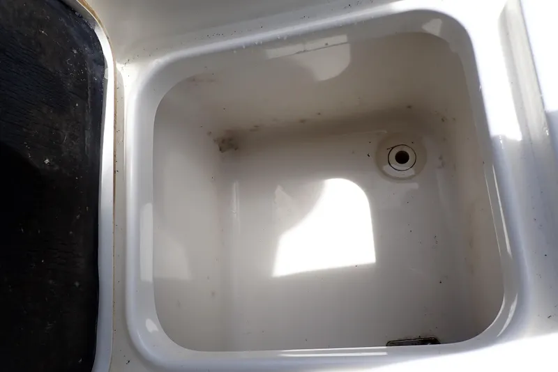 Slide: The Image of 2022 Key West 188 Bay Reef boat storage compartment, white interior, with drain hole. - 33