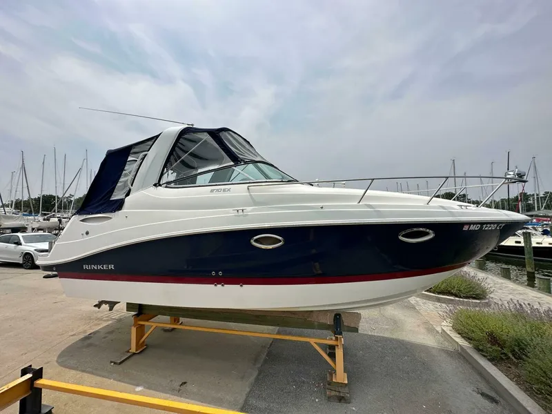 Slide: The Image of 2018 Rinker EX 270 boat on a stand at a marina. - 2