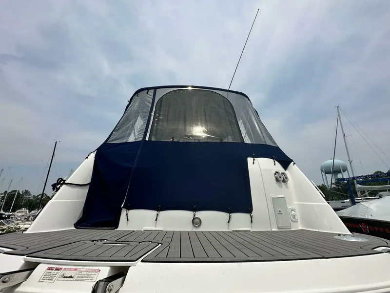 Slide: The Image of 2018 Rinker EX 270 boat with blue canopy, docked under cloudy sky. - 22
