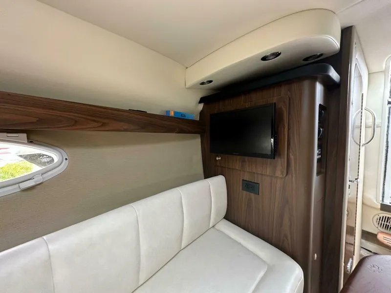 Slide: The Image of Interior of 2018 Rinker EX 270 boat with white seating and wall-mounted TV. - 25