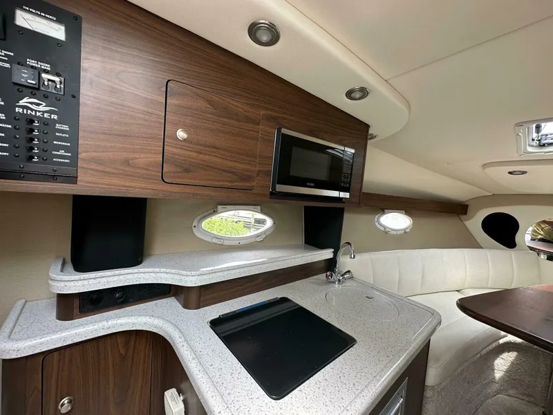 Slide: The Image of 2018 Rinker EX 270 boat interior with kitchenette, microwave, and seating area. - 27