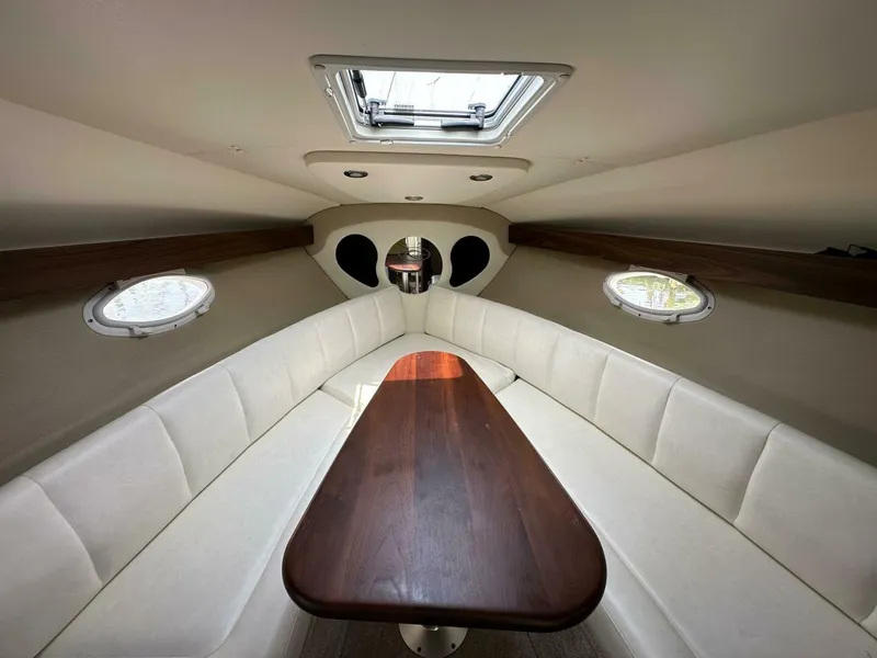 Slide: The Image of 2018 Rinker EX 270 cabin interior with white seating and wooden table. - 31