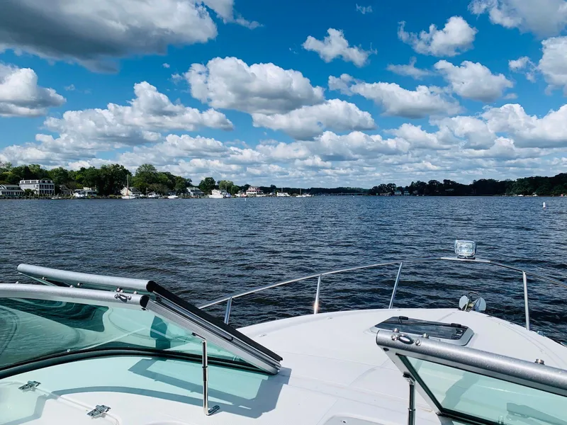 Slide: The Image of 2018 Rinker EX 270 boat cruising on a scenic lake under a cloudy blue sky. - 9