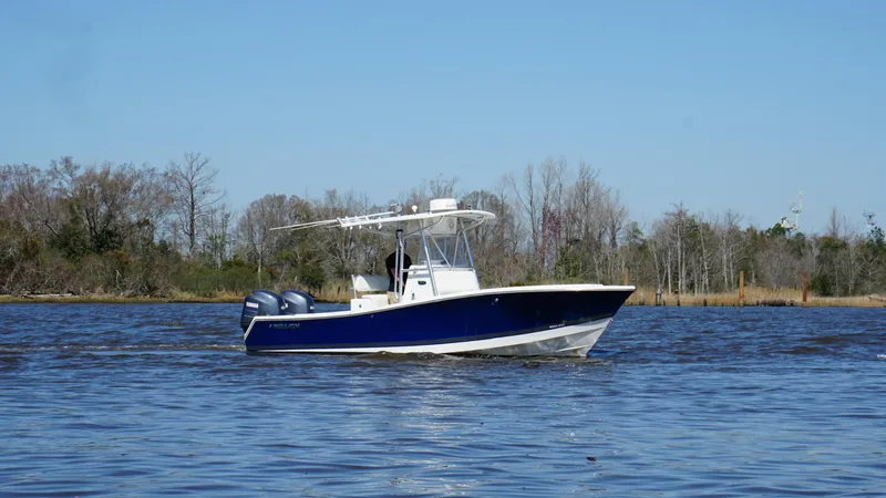 The Image of 2005 Regulator 24 FS boat cruising on a calm lake with trees in the background. - 1