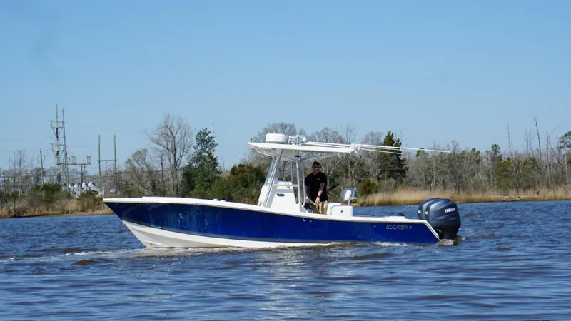Slide: The Image of 2005 Regulator 24 FS boat cruising on a calm river under a clear blue sky. - 3