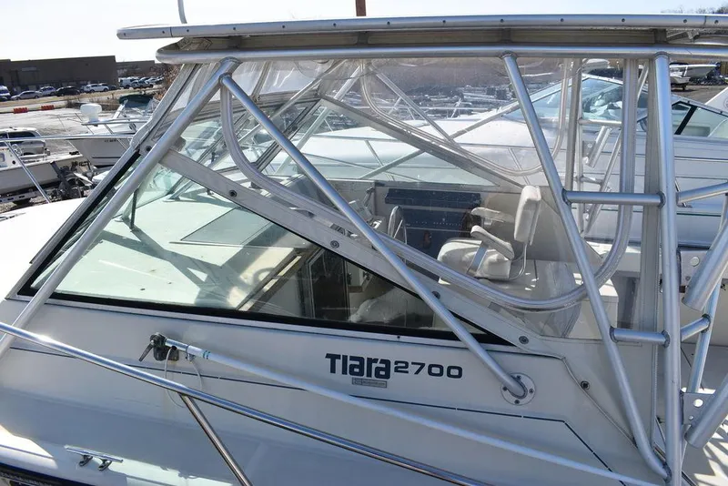 Slide: The Image of 1984 Tiara Sport 2700 boat with glass cabin and metal framework, docked in a marina. - 10