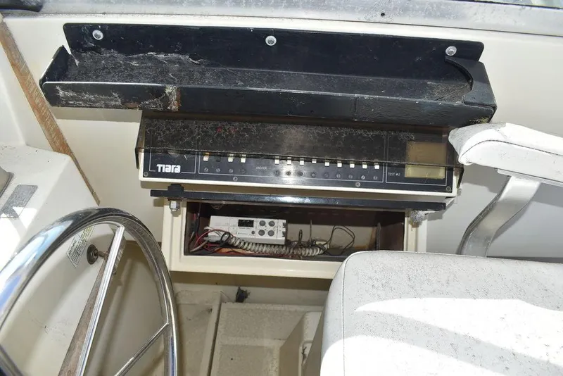 Slide: The Image of 1984 Tiara Sport 2700 boat dashboard with steering wheel and control panel. - 23