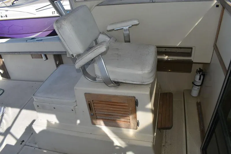 Slide: The Image of Captain's chair on 1984 Tiara Sport 2700 boat, featuring a wooden storage compartment. - 25