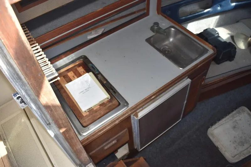 Slide: The Image of 1984 Tiara Sport 2700 boat interior with kitchenette, sink, and wooden cabinetry. - 28
