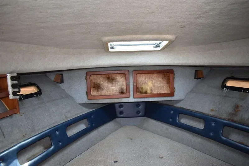Slide: The Image of Interior cabin of a 1984 Tiara Sport 2700 boat, featuring cushioned seating and wooden accents. - 30