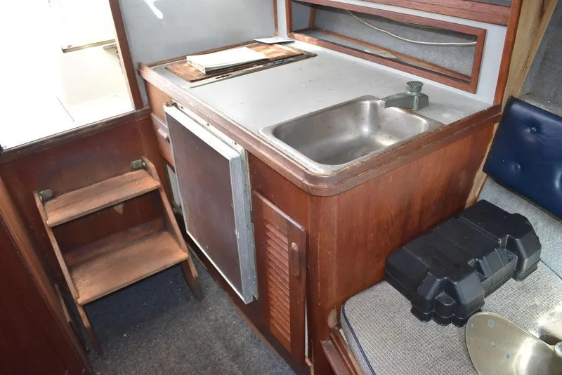 Slide: The Image of 1984 Tiara Sport 2700 boat interior with wooden cabinetry, sink, and compact kitchen area. - 33