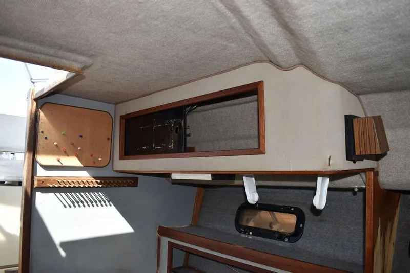 Slide: The Image of Interior of a 1984 Tiara Sport 2700 boat, featuring wooden cabinetry and a small window. - 34