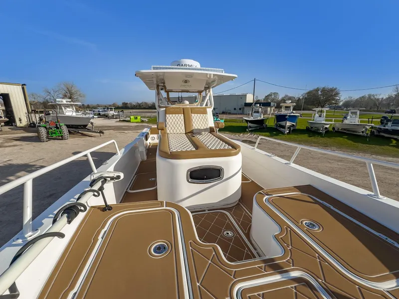 Slide: The Image of 2019 Shallow Sport 32 X3 boat with tan deck, spacious seating, and clear blue sky background. - 16