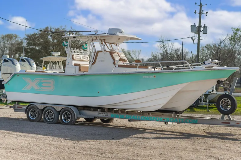 Slide: The Image of 2019 Shallow Sport 32 X3 boat on trailer, turquoise hull, parked outdoors. - 5