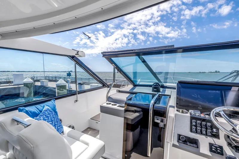 Slide: The Image of 2022 Regal 36 XO yacht cockpit with modern controls, overlooking a sunny ocean view. - 13