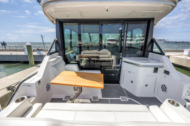 Slide: The Image of 2022 Regal 36 XO yacht with spacious deck, seating, and table, docked at marina. - 9