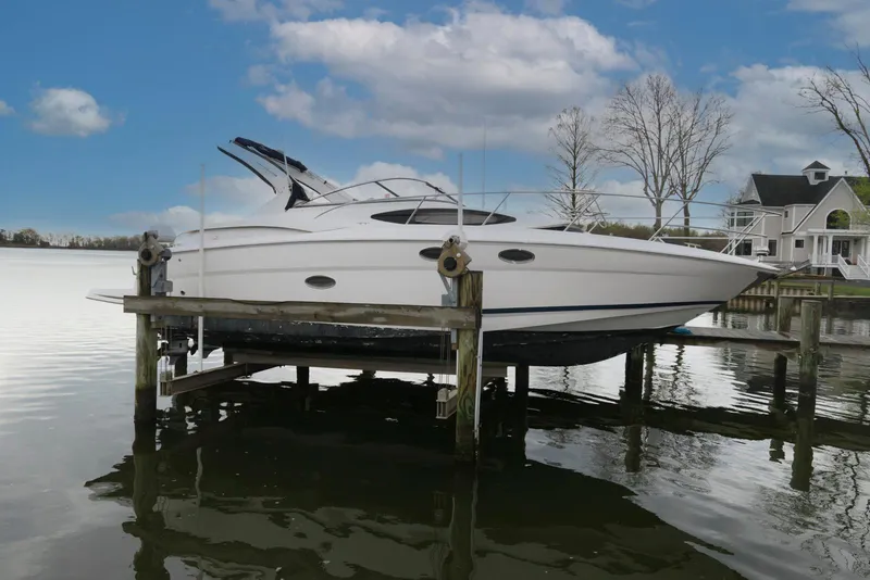 The Image of 2007 Regal 3360 Window Express boat docked by a lakeside house under a cloudy sky. - 0