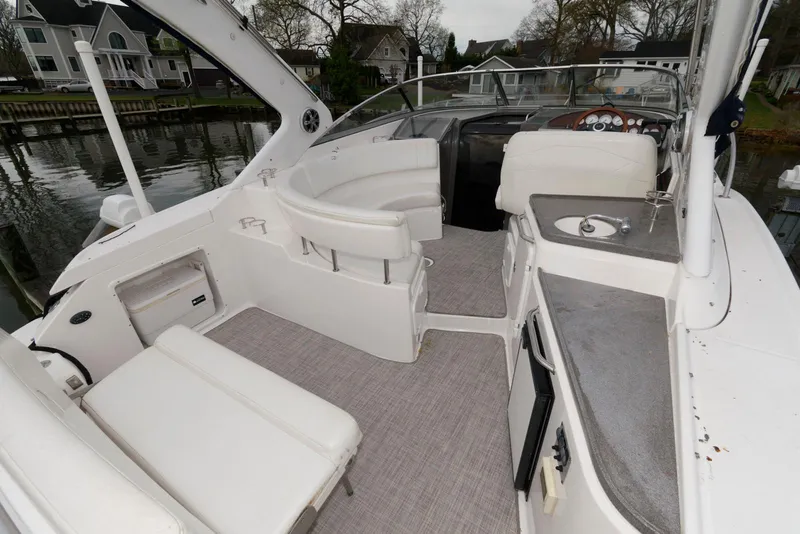 Slide: The Image of 2007 Regal 3360 Window Express boat interior with seating and helm, docked by waterfront homes. - 2