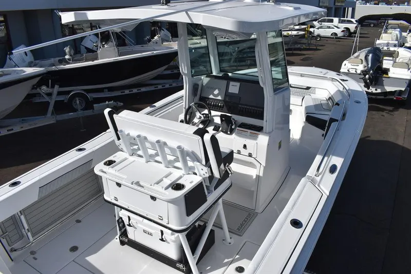 Slide: The Image of 2025 Blackfin 252CC boat with modern console and seating, docked at a marina. - 11