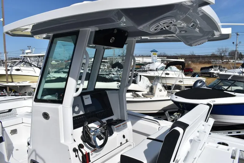 Slide: The Image of 2025 Blackfin 252CC boat console with modern controls and seating, docked among other boats. - 16