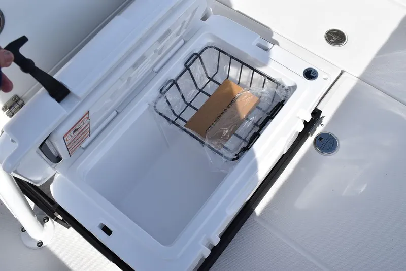 Slide: The Image of Open storage compartment on 2025 Blackfin 252CC boat with basket and package inside. - 39