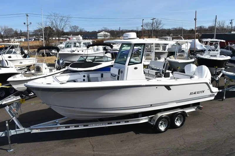 Slide: The Image of 2025 Blackfin 252CC boat on trailer, displayed in a marina with other boats. - 4
