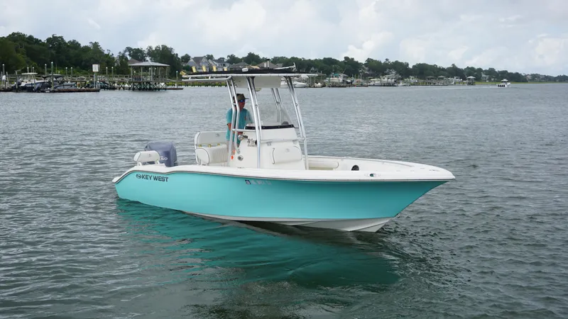 Slide: The Image of 2008 Key West 211 Bluewater boat on calm water, with a person at the helm. - 1