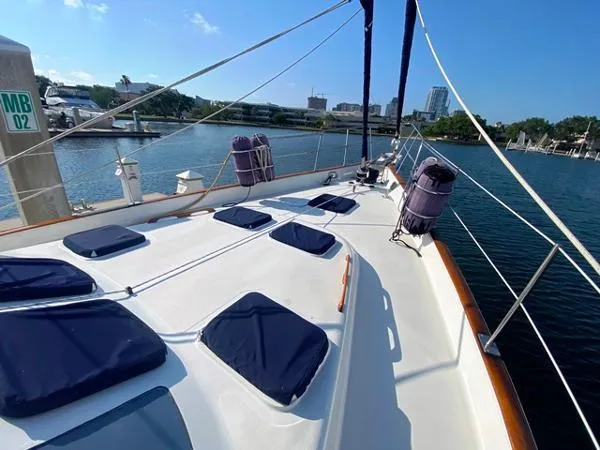 Slide: The Image of 1989 Irwin 54 yacht deck with blue cushions, docked in a marina under clear skies. - 11