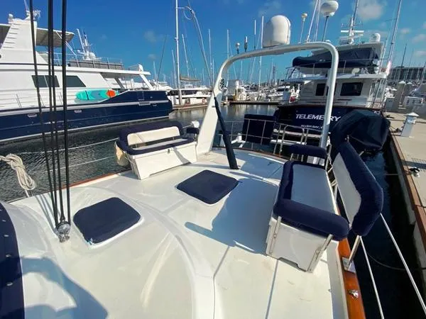 Slide: The Image of 1989 Irwin 54 yacht deck with seating, docked in a marina under clear blue skies. - 16