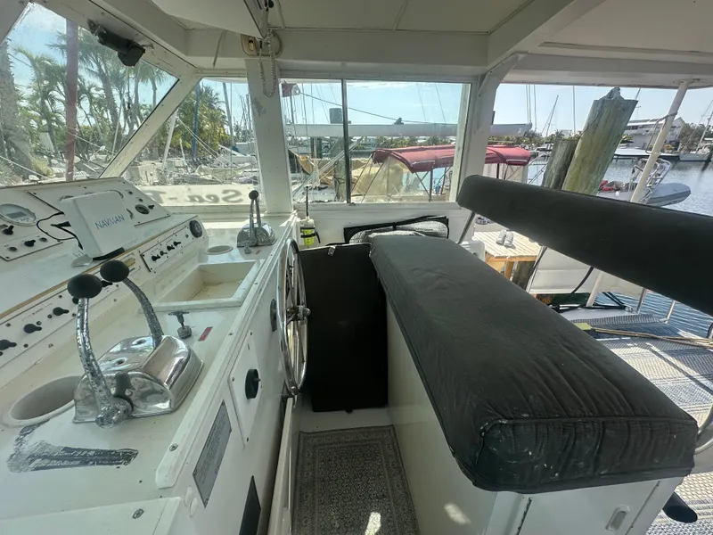 Slide: The Image of 1974 Bertram 42 Motor Yacht helm with controls, seating, and marina view. - 29