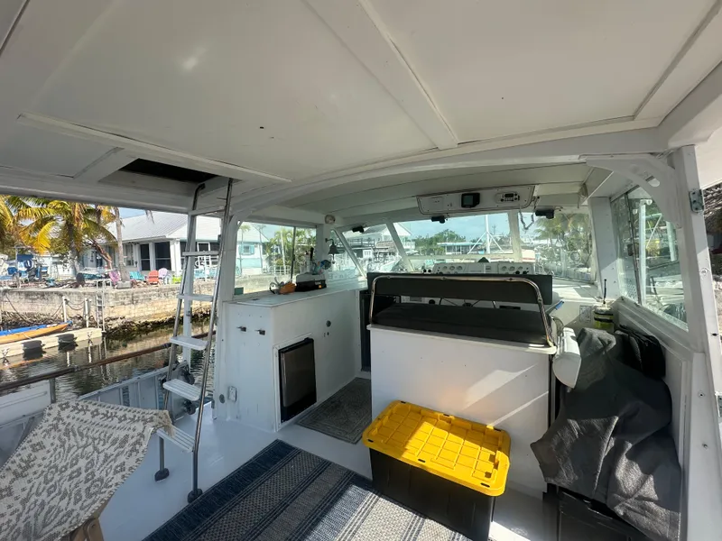 Slide: The Image of 1974 Bertram 42 Motor Yacht interior with seating, storage, and marina view. - 32